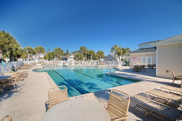 community pool with french doors, fence, and a patio