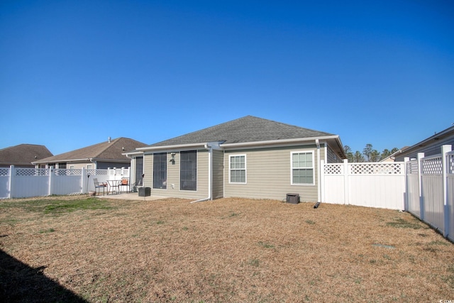 rear view of property with a yard, a patio, a fenced backyard, and roof with shingles