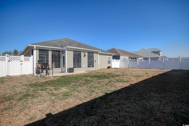 rear view of property with a lawn, a fenced backyard, and a gate