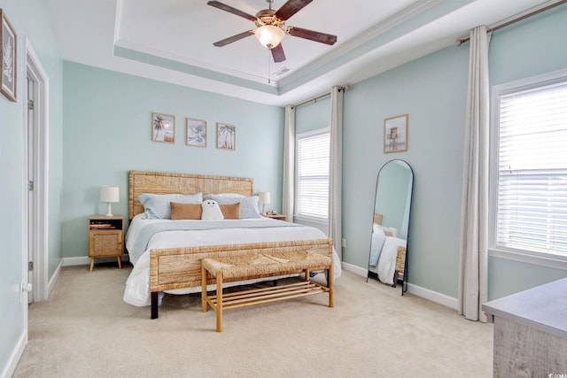 bedroom featuring light carpet, multiple windows, a raised ceiling, and baseboards