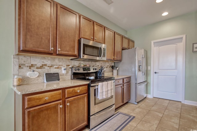 kitchen featuring stainless steel appliances, light tile patterned flooring, backsplash, and baseboards