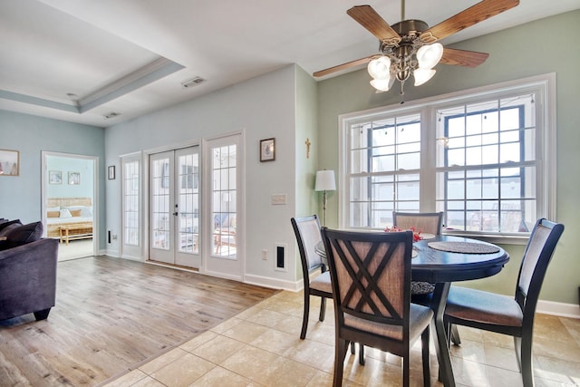 dining room with french doors, a raised ceiling, visible vents, light wood-style flooring, and baseboards