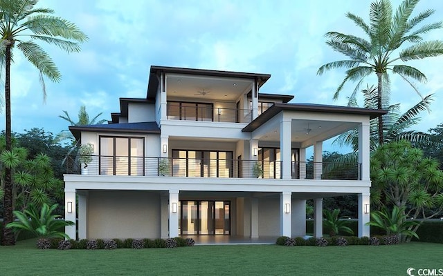 rear view of house with a lawn, a balcony, and stucco siding