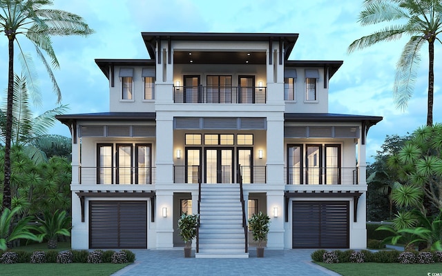 view of front of house featuring a garage, decorative driveway, a balcony, and stucco siding