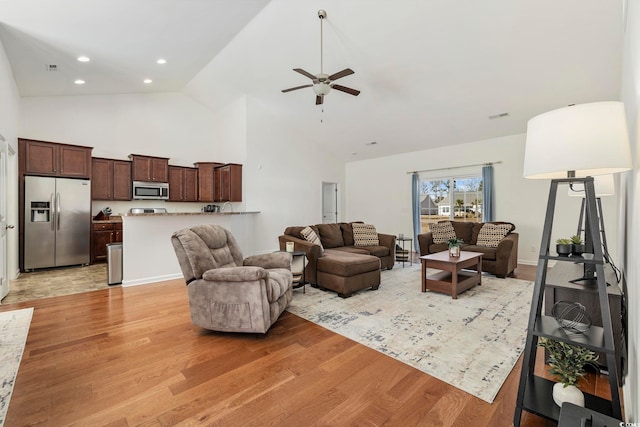 living room featuring ceiling fan, high vaulted ceiling, and light wood-type flooring