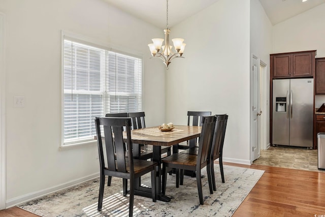 dining room with lofted ceiling, a notable chandelier, and light hardwood / wood-style flooring