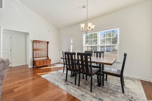 dining room featuring wood-type flooring, high vaulted ceiling, and an inviting chandelier