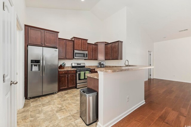 kitchen featuring stainless steel appliances, high vaulted ceiling, light stone countertops, washer / clothes dryer, and kitchen peninsula