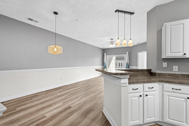 kitchen with white cabinetry, decorative light fixtures, kitchen peninsula, and a textured ceiling