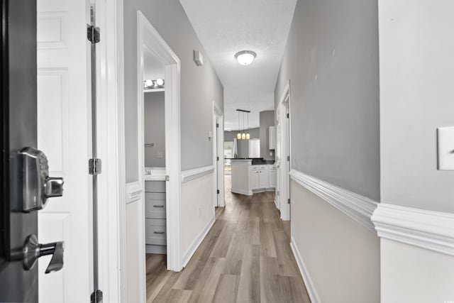 corridor with a textured ceiling and light wood-type flooring