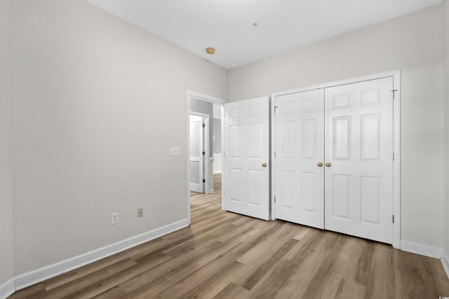 unfurnished bedroom featuring light hardwood / wood-style flooring and a closet