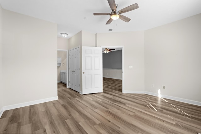 unfurnished bedroom featuring ceiling fan, ensuite bath, and light hardwood / wood-style flooring