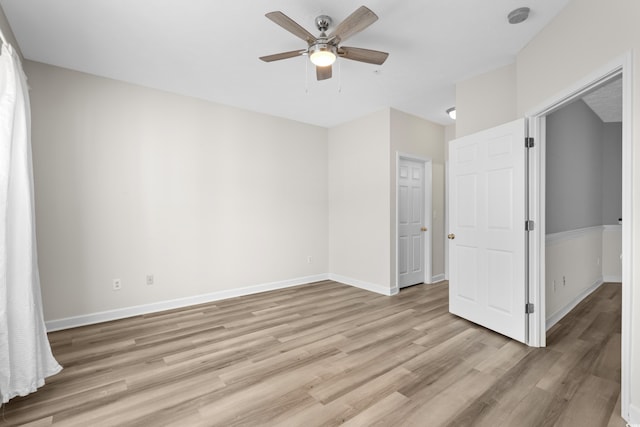 empty room with ceiling fan and light hardwood / wood-style flooring