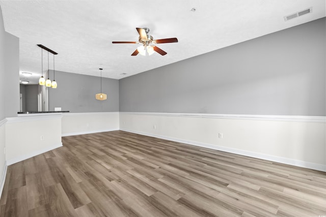 unfurnished living room with wood-type flooring, a textured ceiling, and ceiling fan