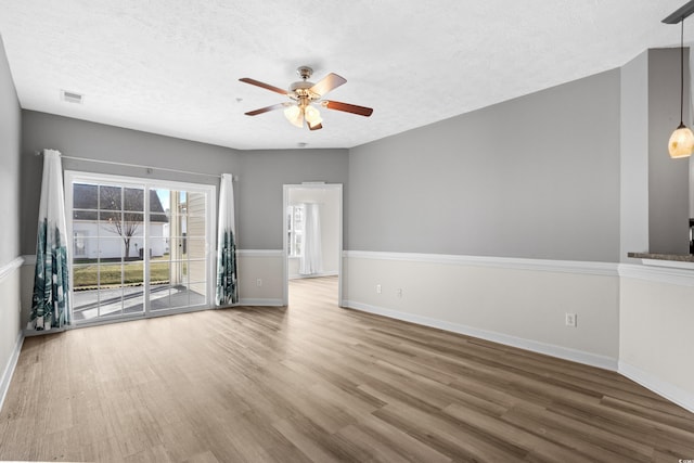 unfurnished living room featuring ceiling fan, hardwood / wood-style floors, and a textured ceiling