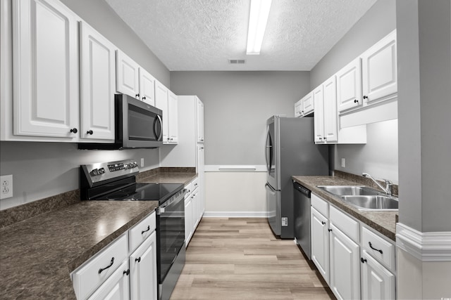 kitchen with white cabinetry, sink, light hardwood / wood-style flooring, and appliances with stainless steel finishes