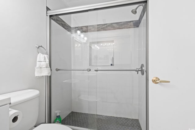 bathroom with a shower with shower door and toilet