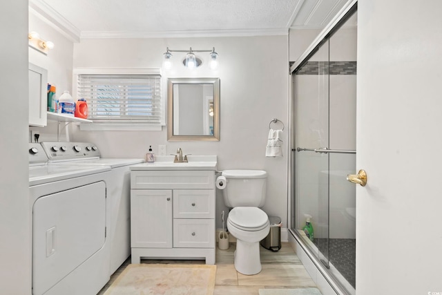 bathroom featuring toilet, a shower with shower door, ornamental molding, vanity, and independent washer and dryer