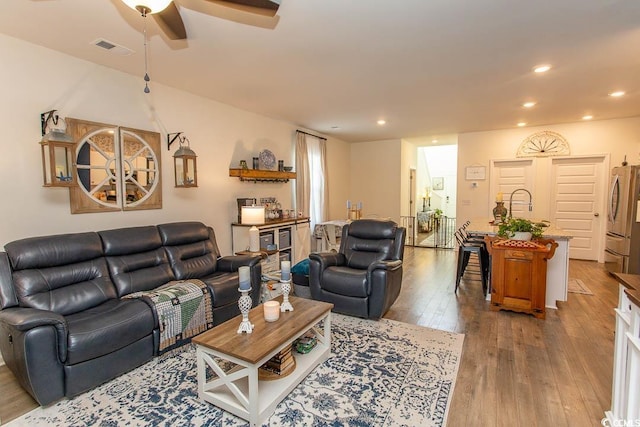 living room with wood-type flooring and ceiling fan