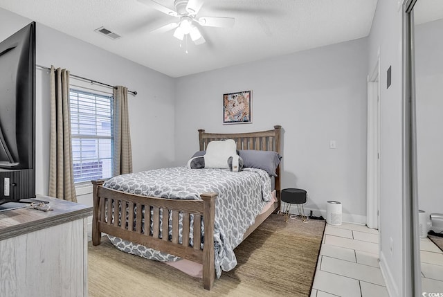 bedroom with ceiling fan, a textured ceiling, and light tile patterned floors