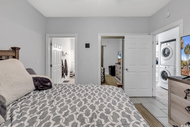 bedroom featuring stacked washer / dryer, light hardwood / wood-style floors, a closet, and a textured ceiling