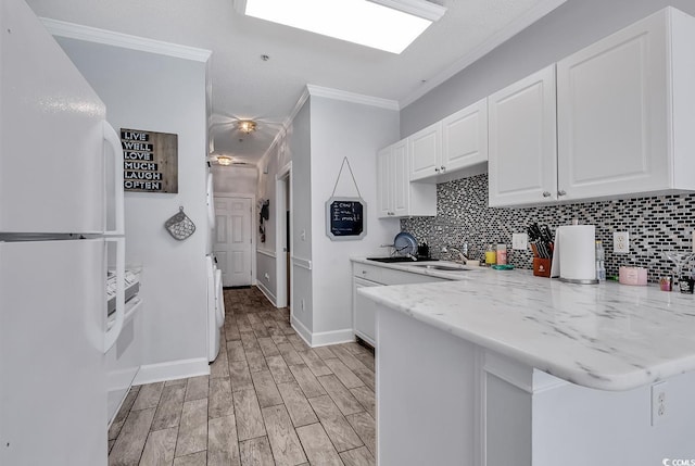 kitchen featuring decorative backsplash, light hardwood / wood-style flooring, white cabinets, and white refrigerator