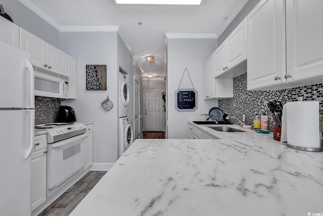 kitchen with stacked washing maching and dryer, sink, white cabinets, light stone counters, and white appliances