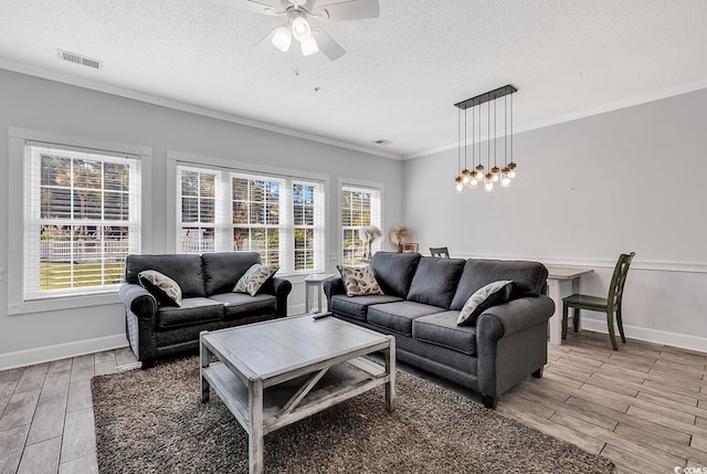 living room featuring ornamental molding, a wealth of natural light, ceiling fan, and a textured ceiling