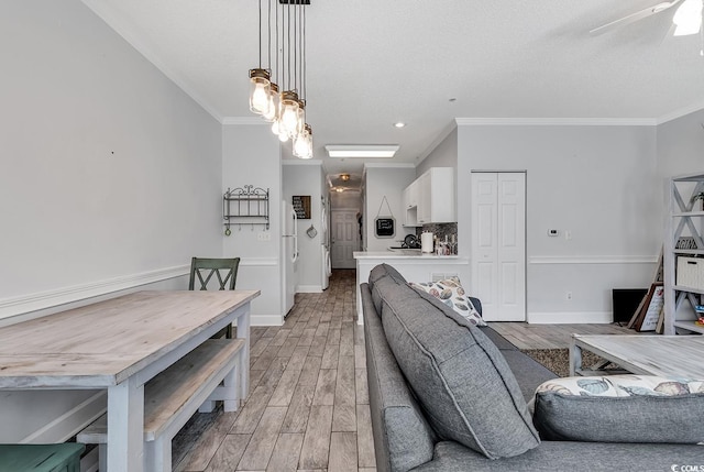 living room with wood-type flooring, ceiling fan, and crown molding