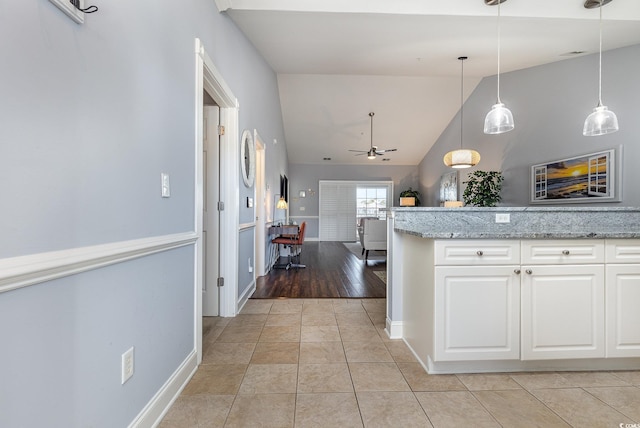 kitchen featuring light tile patterned flooring, white cabinets, hanging light fixtures, ceiling fan, and light stone countertops