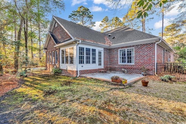 rear view of house featuring a patio area, a yard, brick siding, and fence