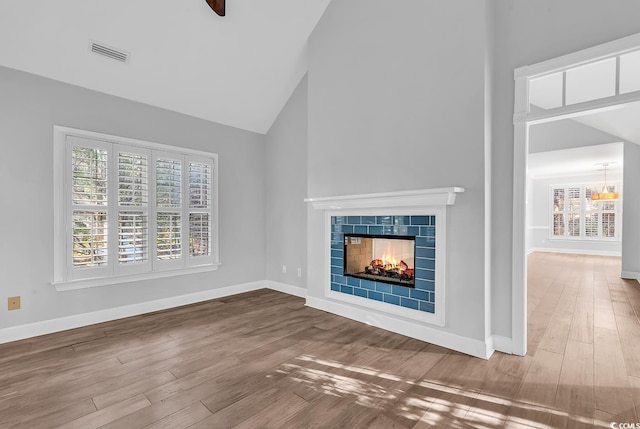 unfurnished living room featuring baseboards, visible vents, a tiled fireplace, and wood finished floors