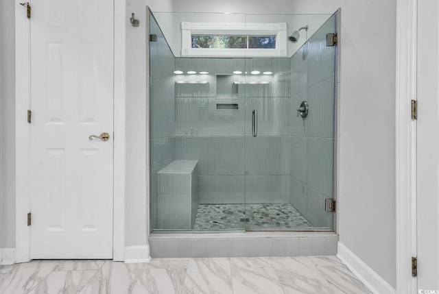 bathroom with marble finish floor, baseboards, and a stall shower