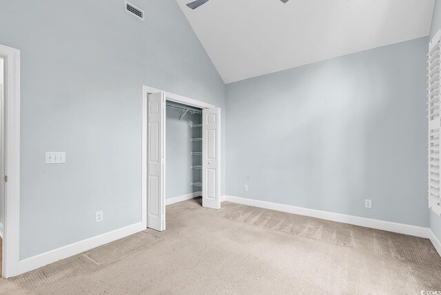 unfurnished bedroom featuring light colored carpet, high vaulted ceiling, and a closet