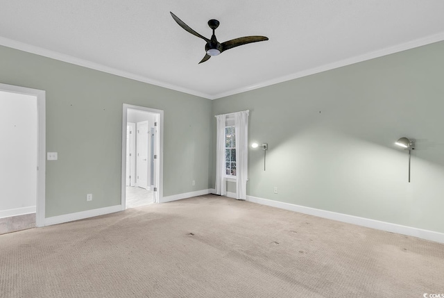 unfurnished room featuring light carpet, ceiling fan, baseboards, and crown molding