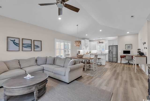 living room featuring ceiling fan, lofted ceiling, sink, and light wood-type flooring