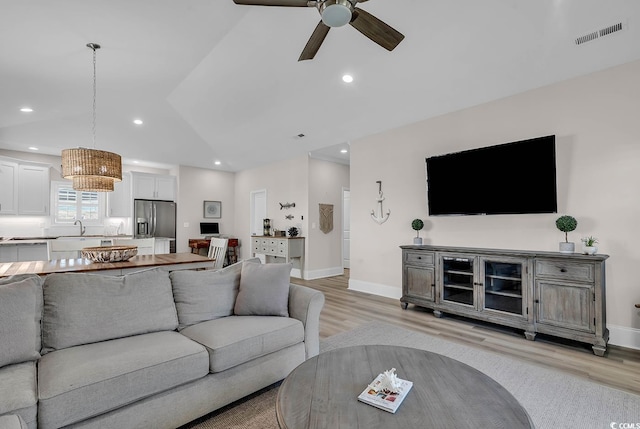 living room with ceiling fan, lofted ceiling, sink, and light hardwood / wood-style floors