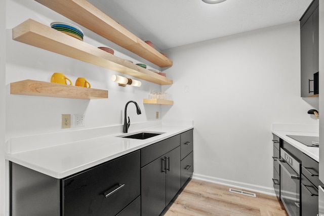 kitchen with black electric cooktop, sink, and light hardwood / wood-style flooring