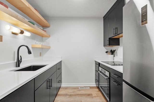 kitchen with stainless steel appliances, sink, and light hardwood / wood-style floors