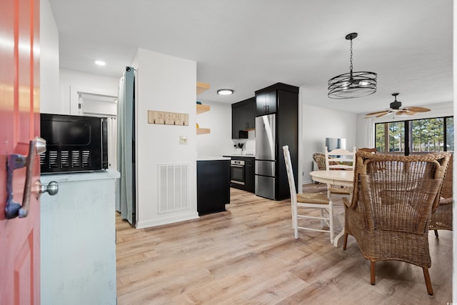 kitchen featuring stainless steel refrigerator, ceiling fan, oven, and light wood-type flooring