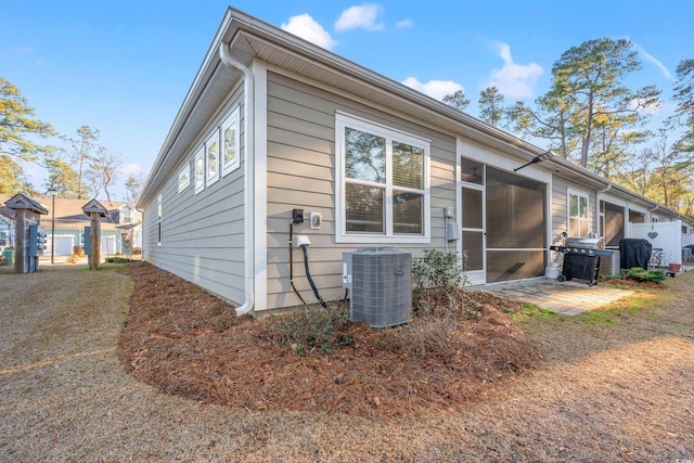 view of side of home featuring a patio, a sunroom, and central AC unit