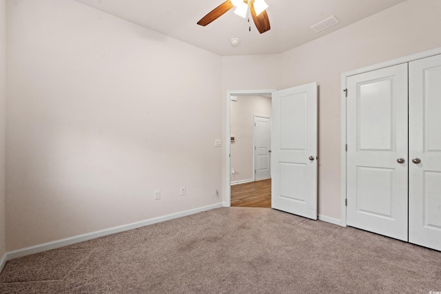 unfurnished bedroom featuring light carpet, ceiling fan, and a closet