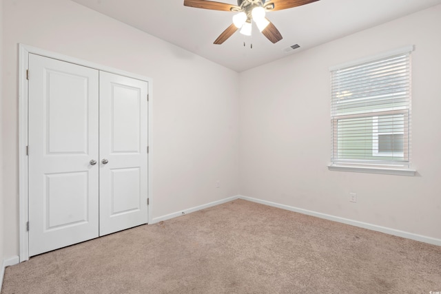 unfurnished bedroom with ceiling fan, a closet, and light carpet