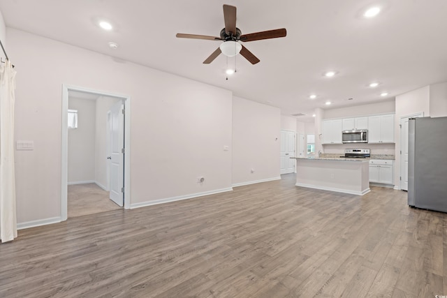 unfurnished living room featuring ceiling fan and light hardwood / wood-style flooring