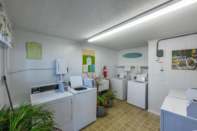 clothes washing area with sink, a textured ceiling, and washing machine and clothes dryer