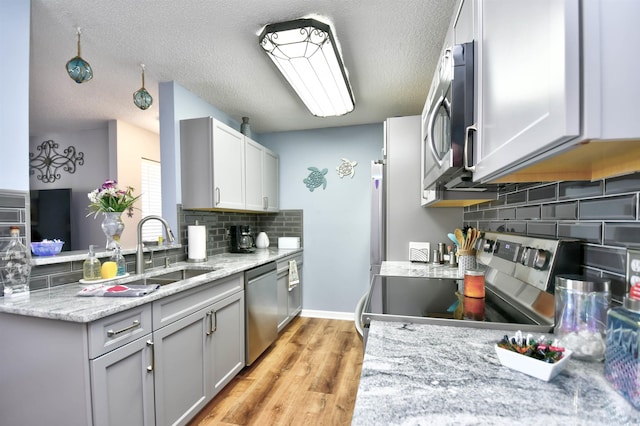 2225 Essex Dr Unit F, Surfside Beach, SC 29575 - kitchen featuring a textured ceiling, a sink, light wood-style floors, tasteful backsplash, and appliances with stainless steel finishes