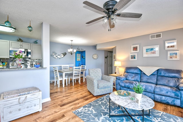 2225 Essex Dr Unit F, Surfside Beach, SC 29575 - living room featuring light wood finished floors, visible vents, a textured ceiling, and ceiling fan with notable chandelier