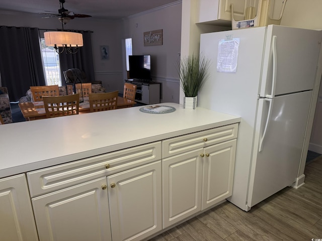 kitchen with white cabinetry, light hardwood / wood-style flooring, white refrigerator, ornamental molding, and ceiling fan