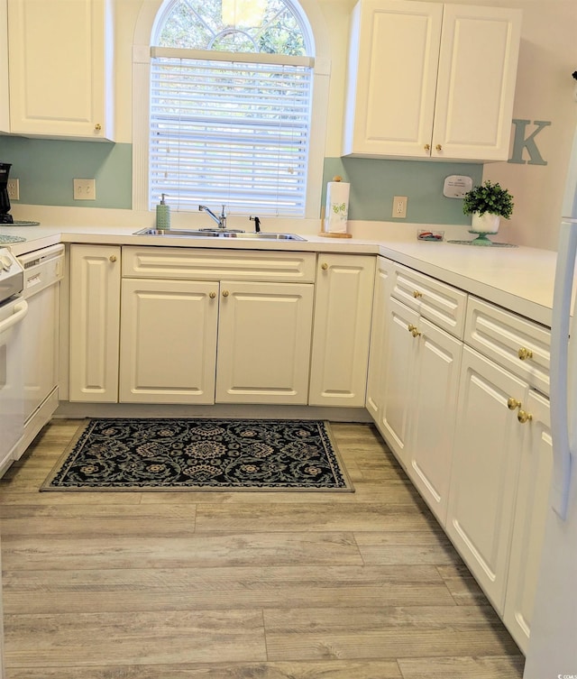 kitchen with white cabinetry, white appliances, sink, and light hardwood / wood-style flooring