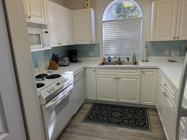 kitchen with white cabinetry, sink, white appliances, and light hardwood / wood-style flooring